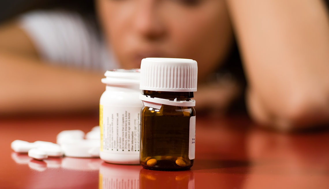 item 9 of Gallery image - Mujer deprimida mirando un frasco de pastillas