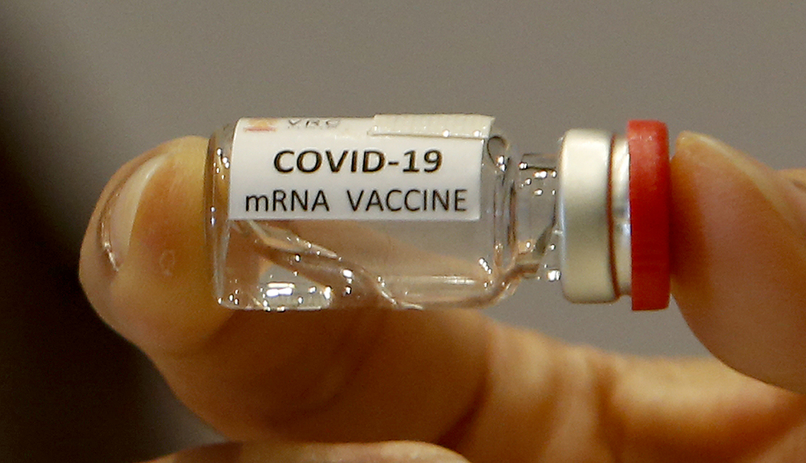 A person holds a vial of mRNA COVID-19 vaccine