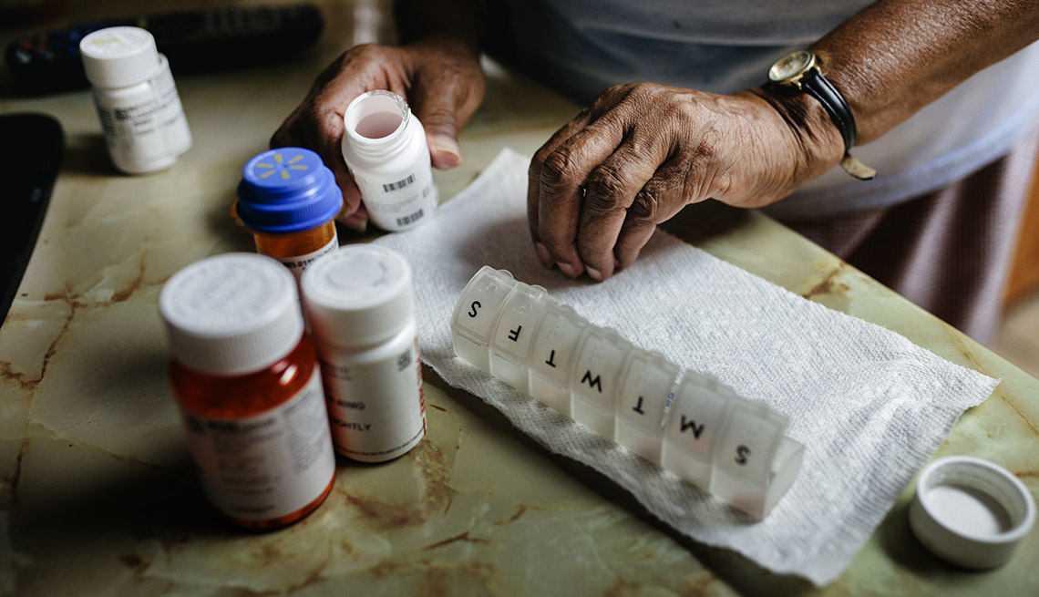 Una mujer alista sus medicamentos en un pastillero para la semana