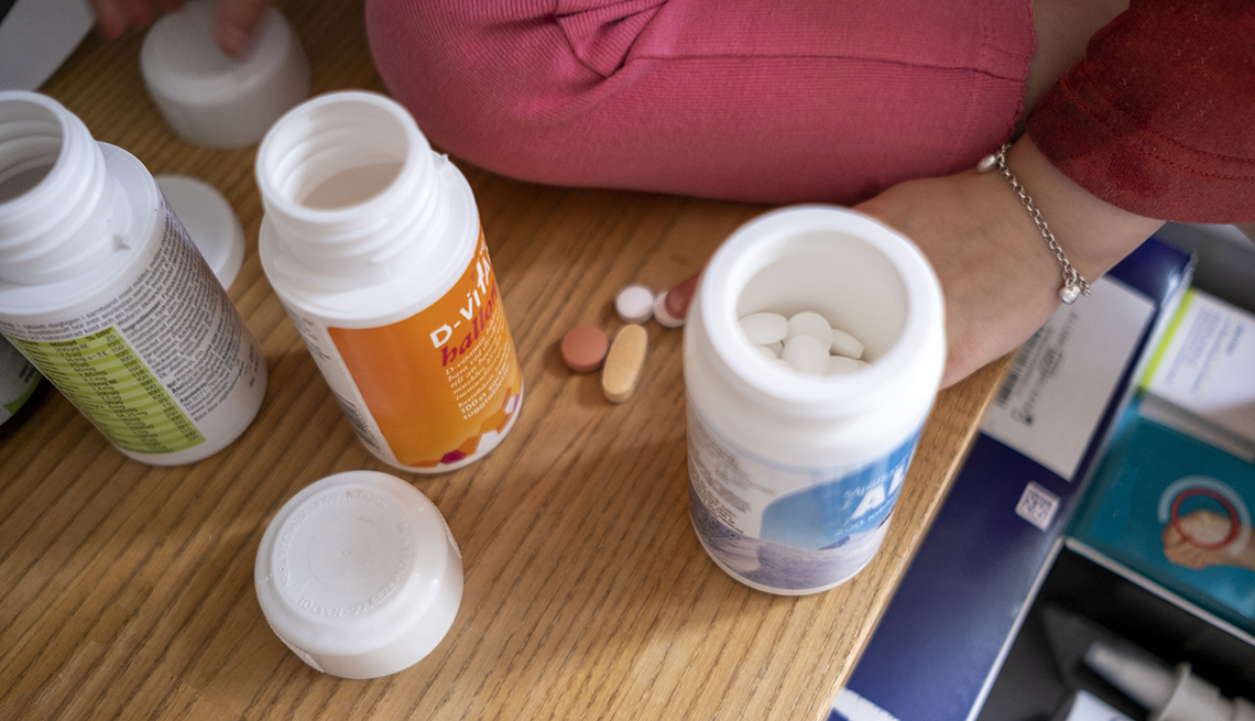 bottles of supplements with a woman's hand nearby, counting the pills