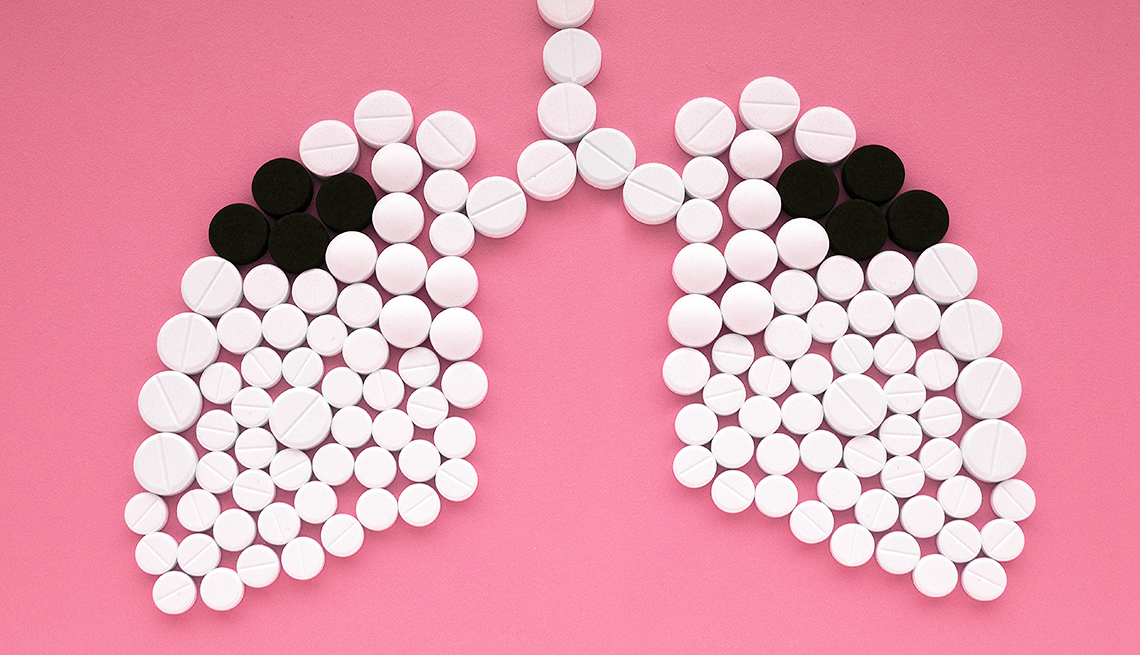 Ilustración de un pulmón lleno de pastillas blancas y negras sobre un fondo rosado.