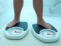 Photo of feet on two scales. An extra ten pounds may help health after age 50. 