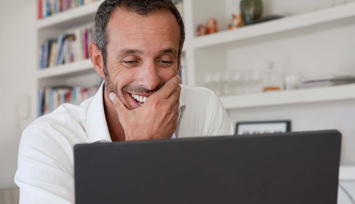 Man laughs at something on laptop, Reduce Stress with humor