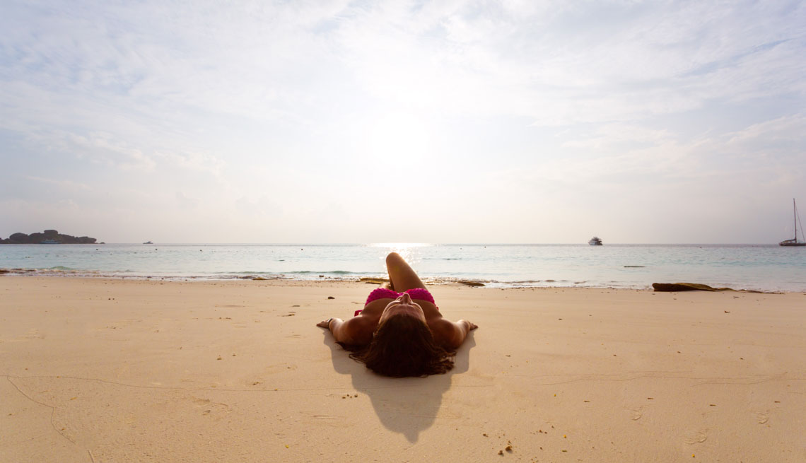 Woman lying on a beach, Stay Healthy on Vacation 