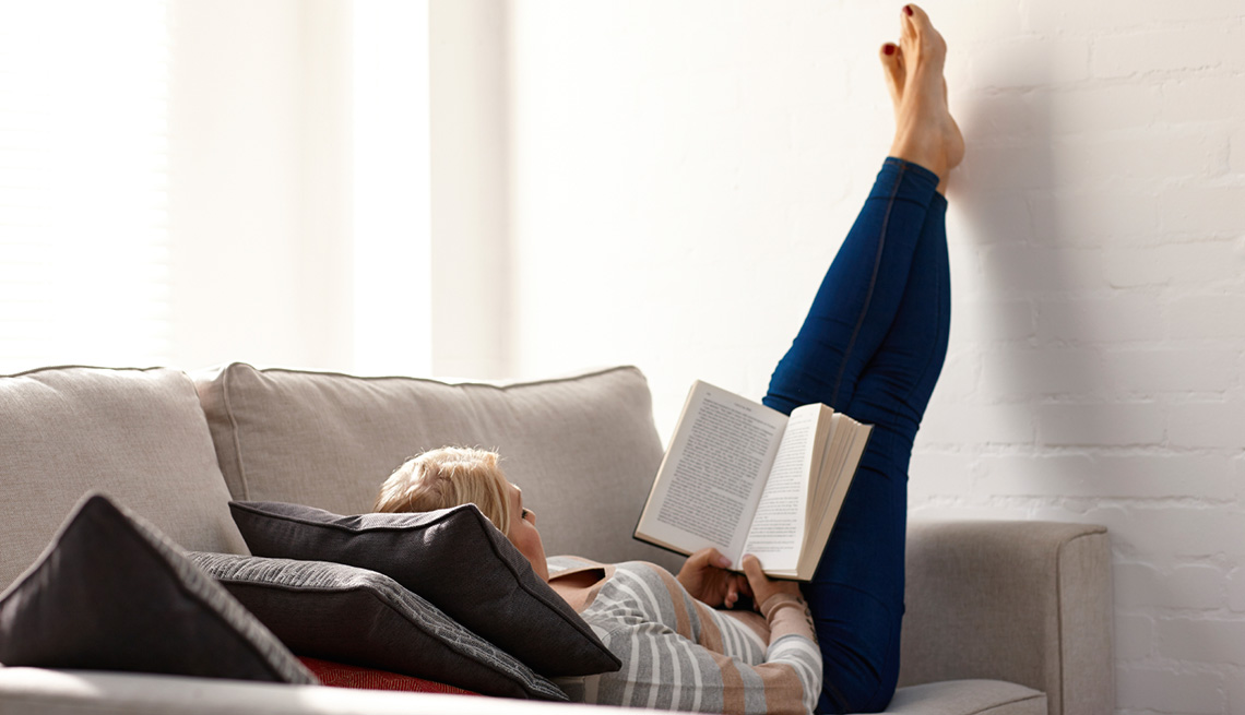 Mujer leyendo muy relajada en un sofá