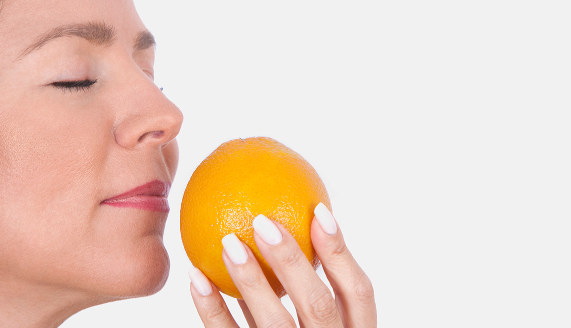 Mujer oliendo una naranja