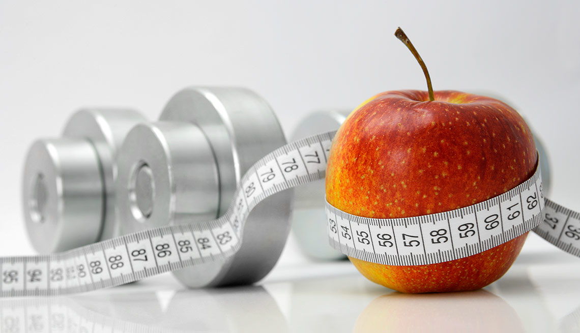 Mancuernas, manzana y cinta de medir