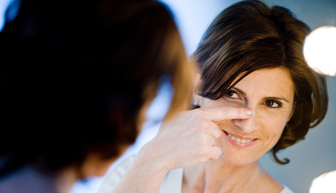 Mujer mirándose al espejo y examinando su nariz