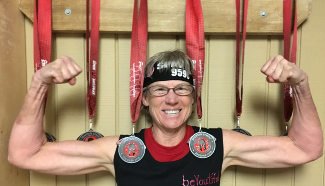 Lynn Asbury flexing in front of her medals