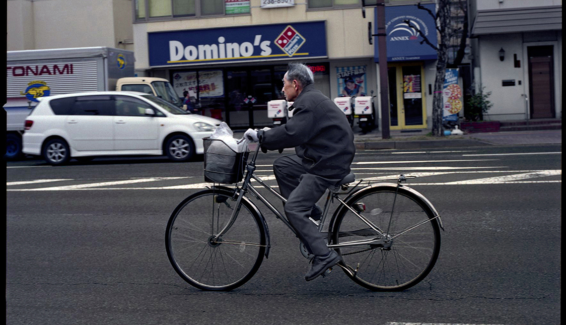 Man bicycling in city, Nagano, Japan, Longest Living place on Earth