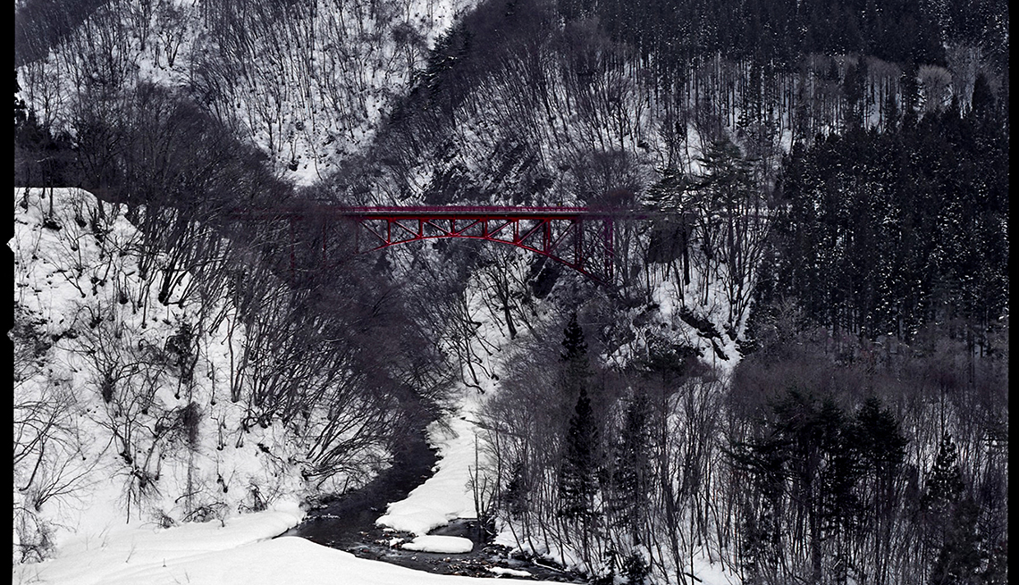 A red bridge in snowy tree covered hills, Yamada-Onsen, Japan, Longest Living place on Earth