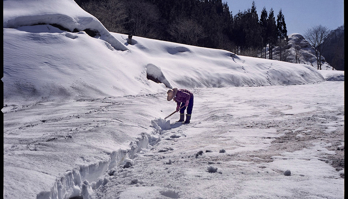 Woman works in snow, sunny snow clearing, Longest Living place on Earth