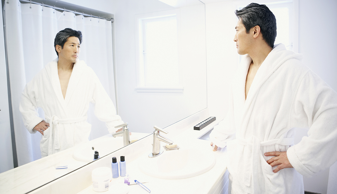 Man in robe looks in a bathroom mirror, 7 Reasons to Have More Sex After 50
