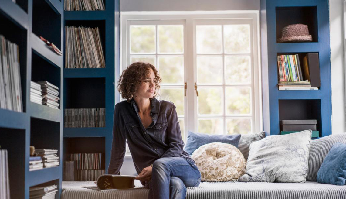 A mature woman sitting in living room with bookshelves, Self-Care Conundrum, Healthly Living