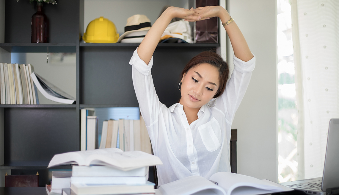 Asian Woman Sitting At Her Office Desk And Stretching, Healthy Tips While Sitting At Your Desk