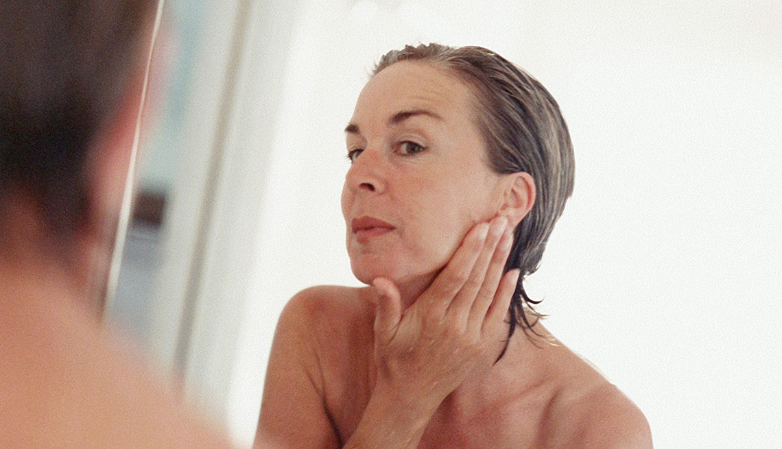 Mujer de mediana edad observando la piel de su cara