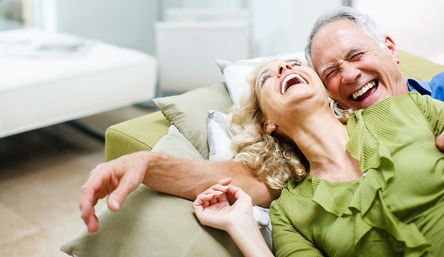couple laughing while sitting on a couch 