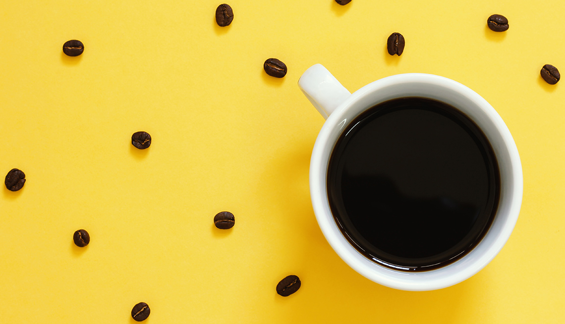 Coffee cup and beans on yellow background