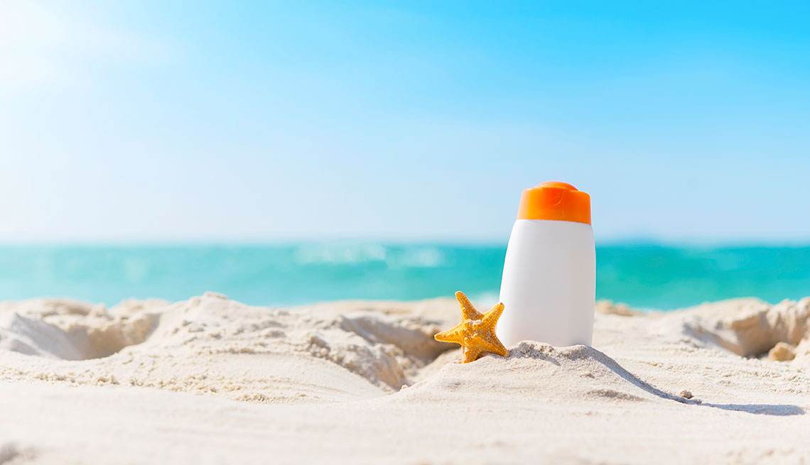Sunblock bottle on the beach with blue sky. UV protection in summer.