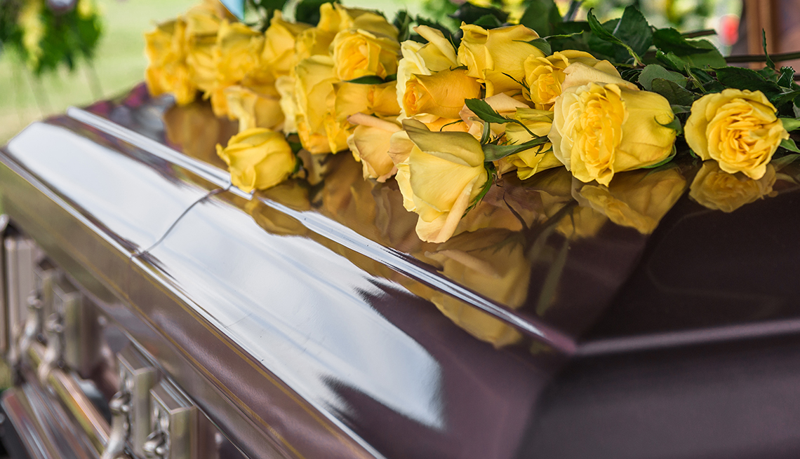 Casket in funeral service with yellow roses on top.