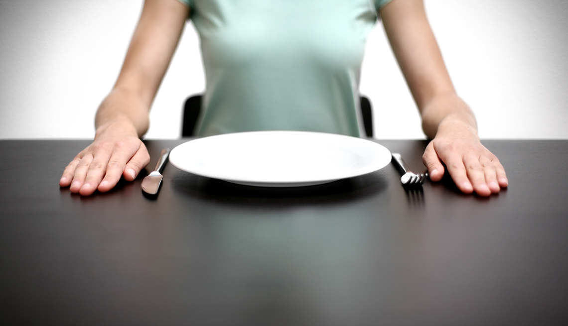 Mujer sentada frente a un plato vacio