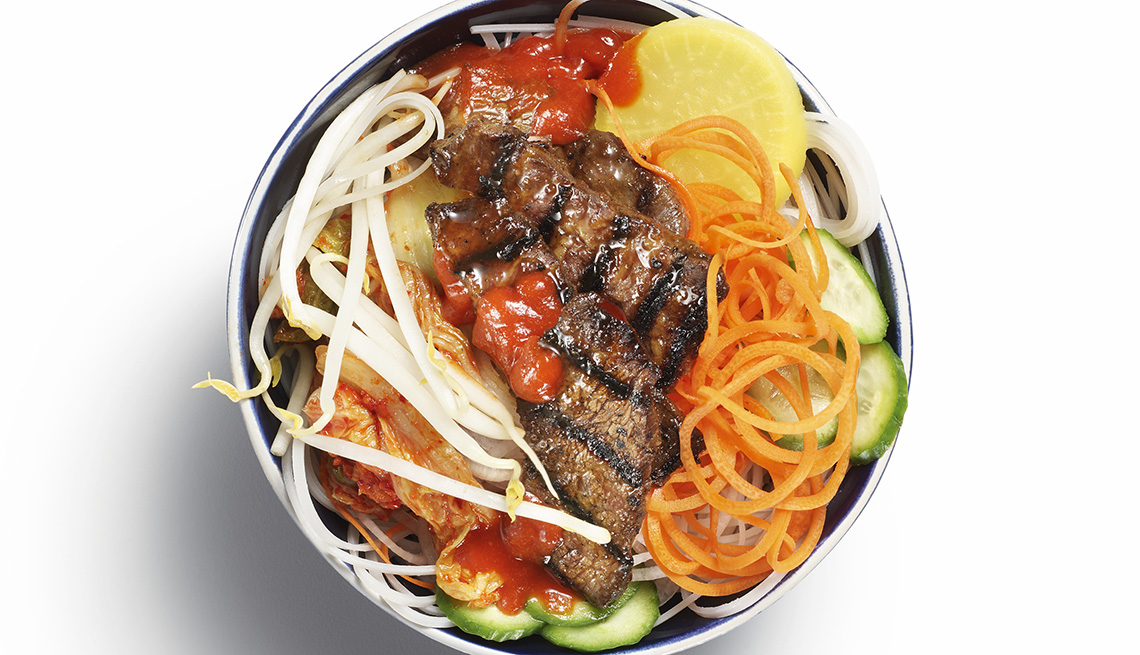 item 1 of Gallery image - Korean food bowl featuring grilled beef, vegetables and noodles.