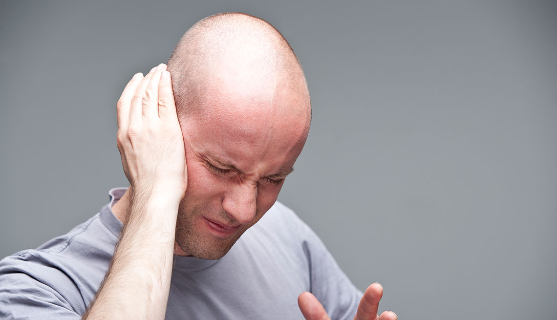 Hombre cubre su oído en señal de dolor