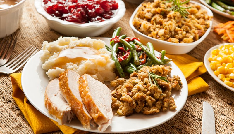 A plated holiday turkey dinner with mashed potatoes gravy stuffing green beans and corn