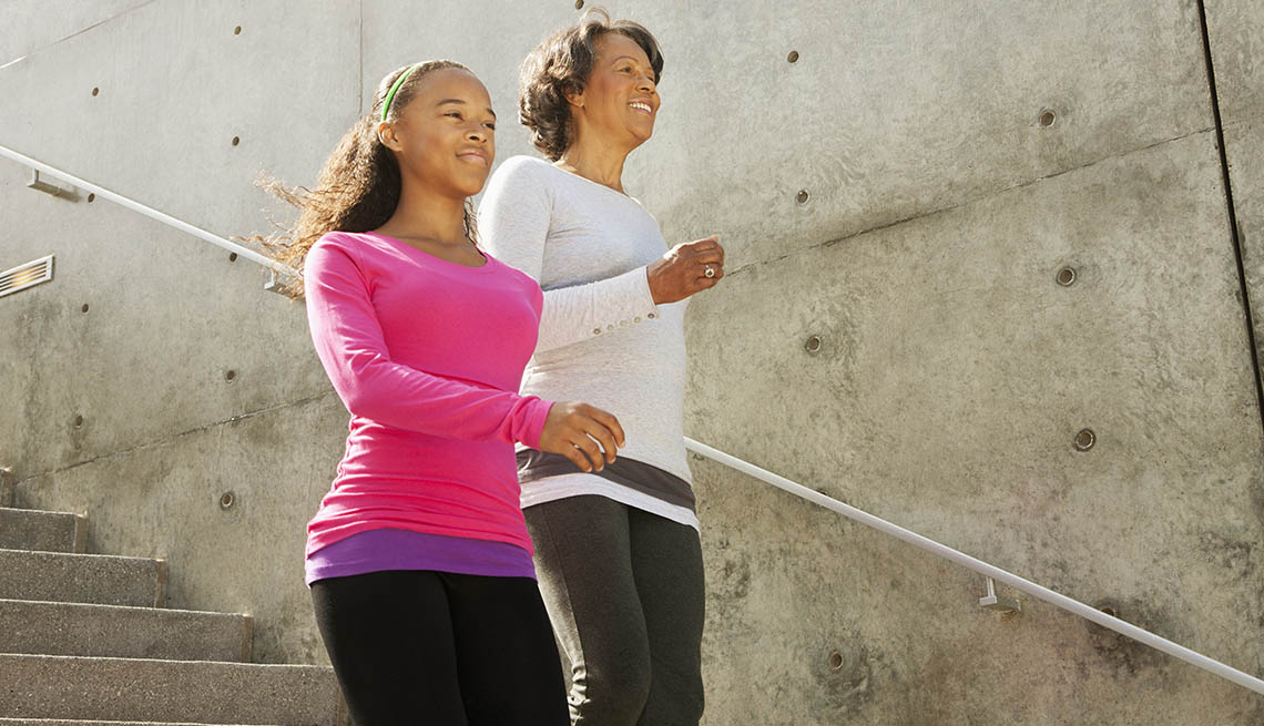 A mother and daughter, both African American walk down stairs outside as they exercise