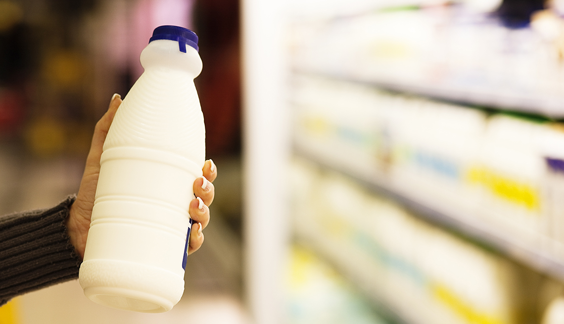 Una mujer sostiene una botella de leche en un supermercado