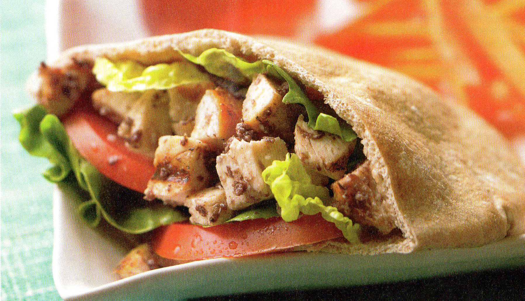 a pita cut in half showing cubed chicken lettuce and tomatoes inside
