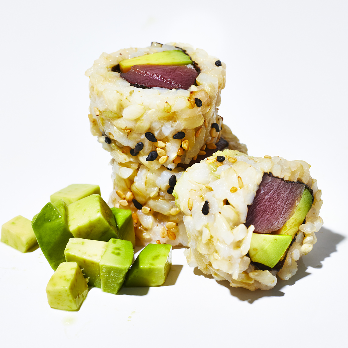 closeup of a few slices of a sushi tuna roll with brown rice and avocado