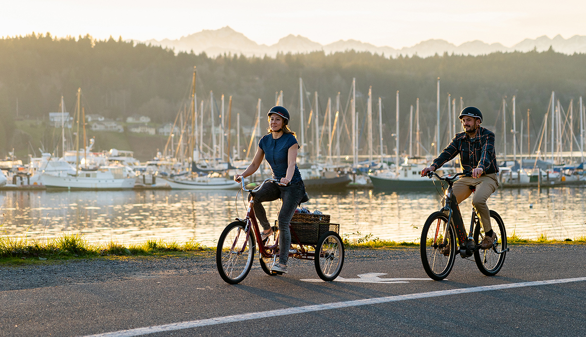two people riding the tristar burg and vida bikes along a pretty harbor