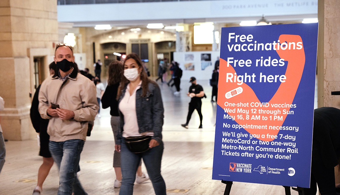 People walk through Grand Central Terminal where a pop-up site for COVID-19 vaccinations opened on May 12, 2021 in New York City. A sign reads free vaccinations - free rides.