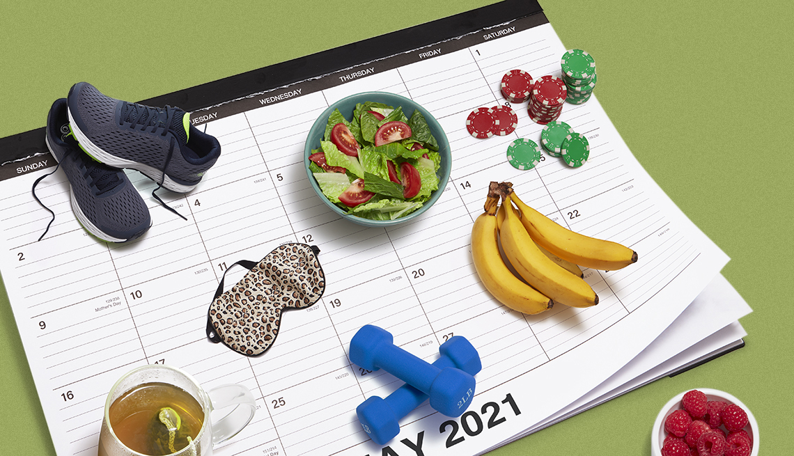 Calendario de escritorio con objetos relacionados a la salud, unas zapatillas de correr, una taza de te, un plato hondo con ensalada, frutas y unas mancuernas