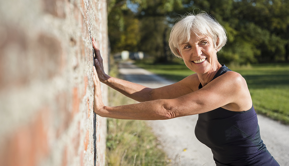 Una mujer hace ejercicios de estiramiento contra una pared