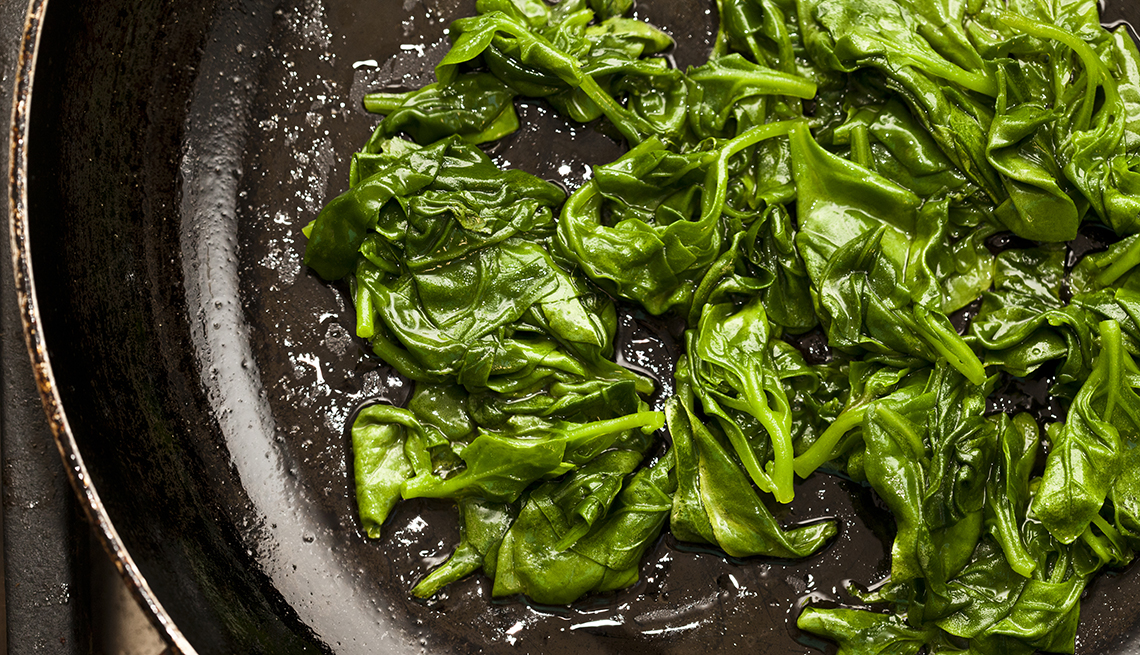 overhead shot of a saute pan with cooking spinach