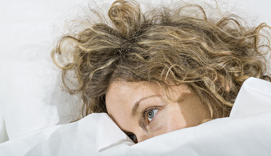 Una mujer acostada en su cama sin poder dormir