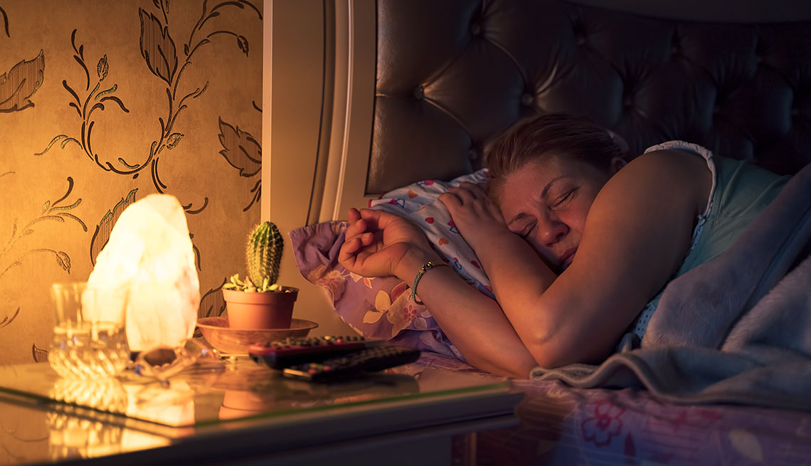 Una mujer duerme con una lámpara encendida