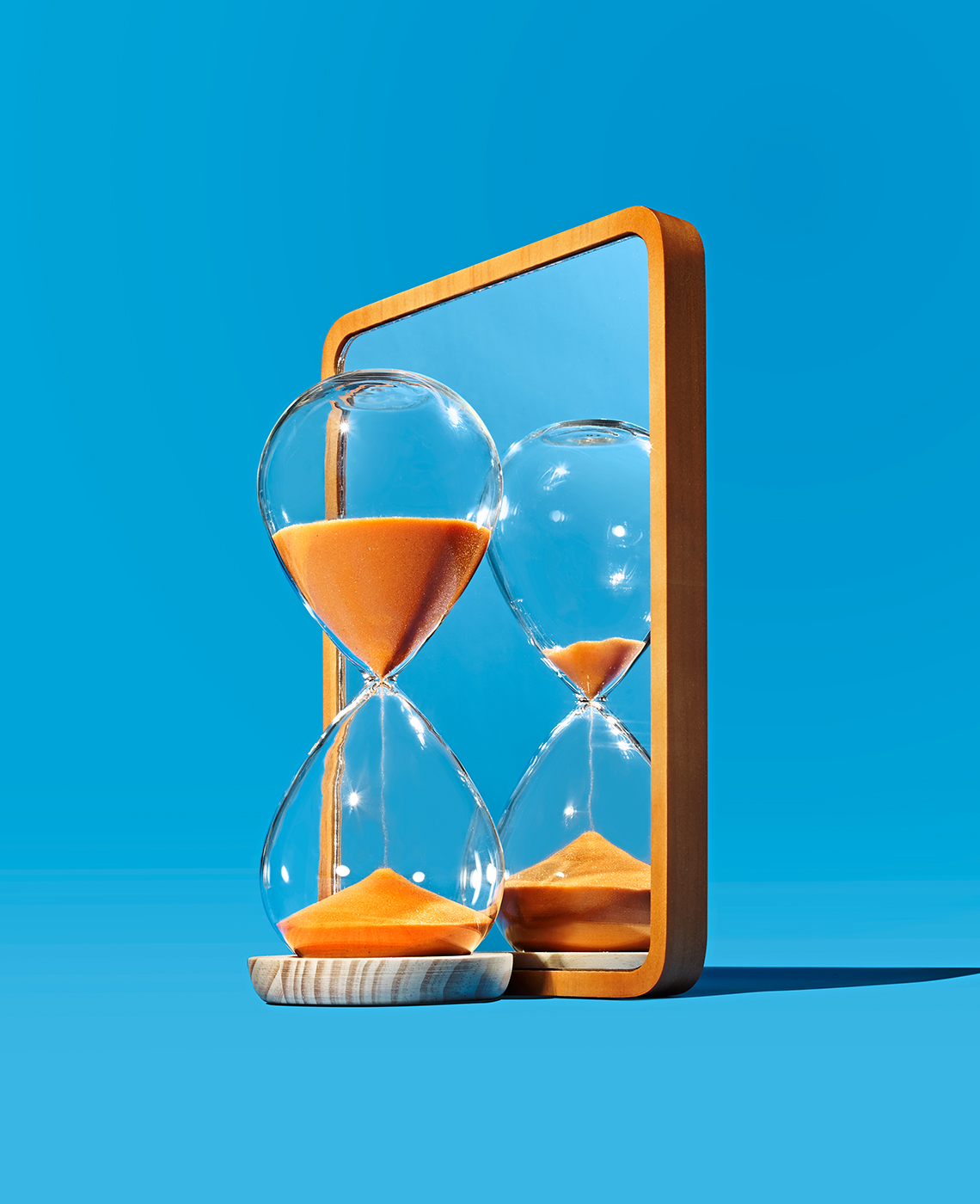 Un reloj de arena frente a un espejo con un fondo azul