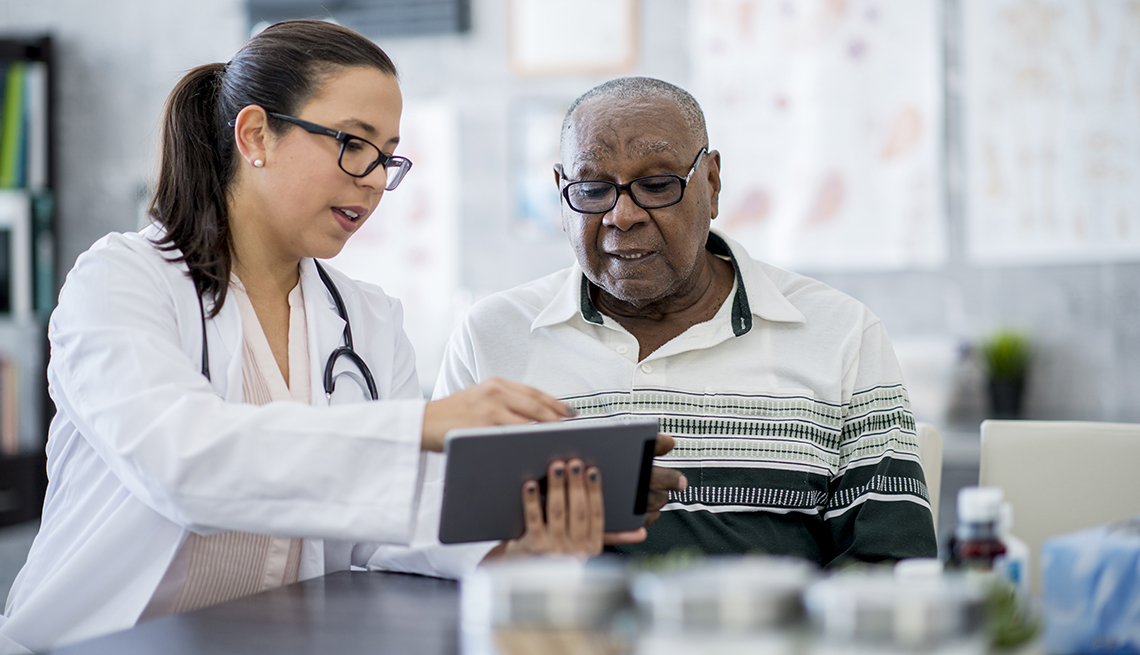 Un hombre junto a su doctora miran a una tabletta