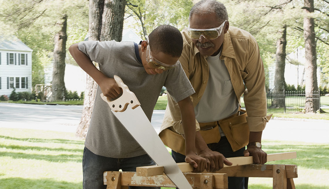 Abuelo y nieto cortan madera y ambos usan protección para los ojos