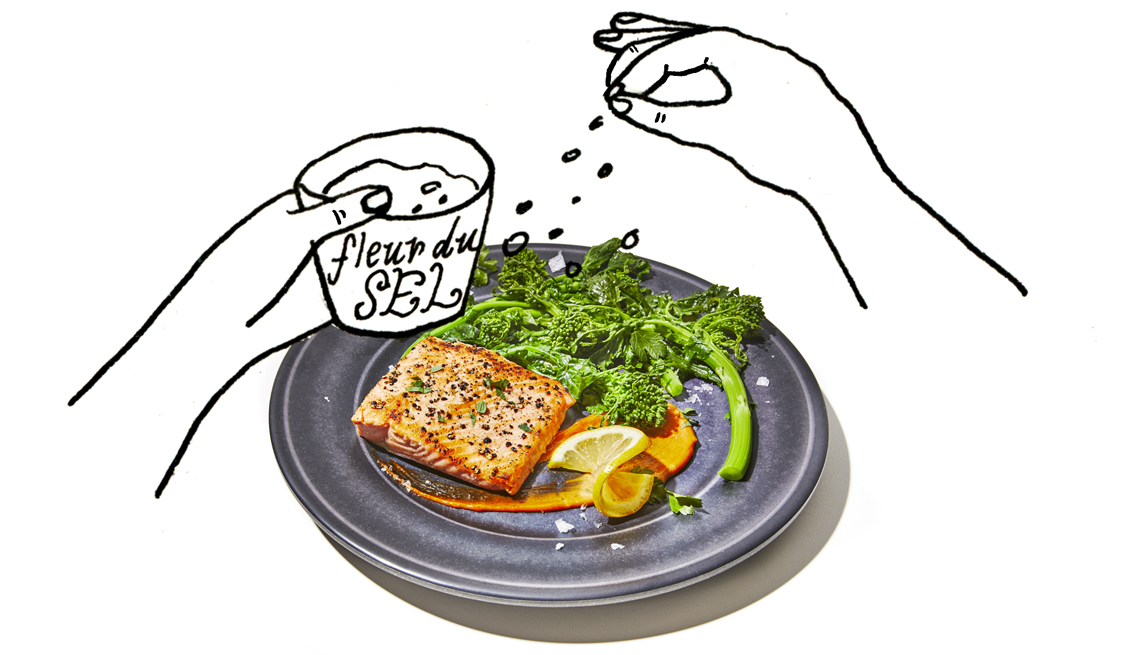 Un plato con verduras y salmón y unas manos dibujadas simulan que le echan sazón