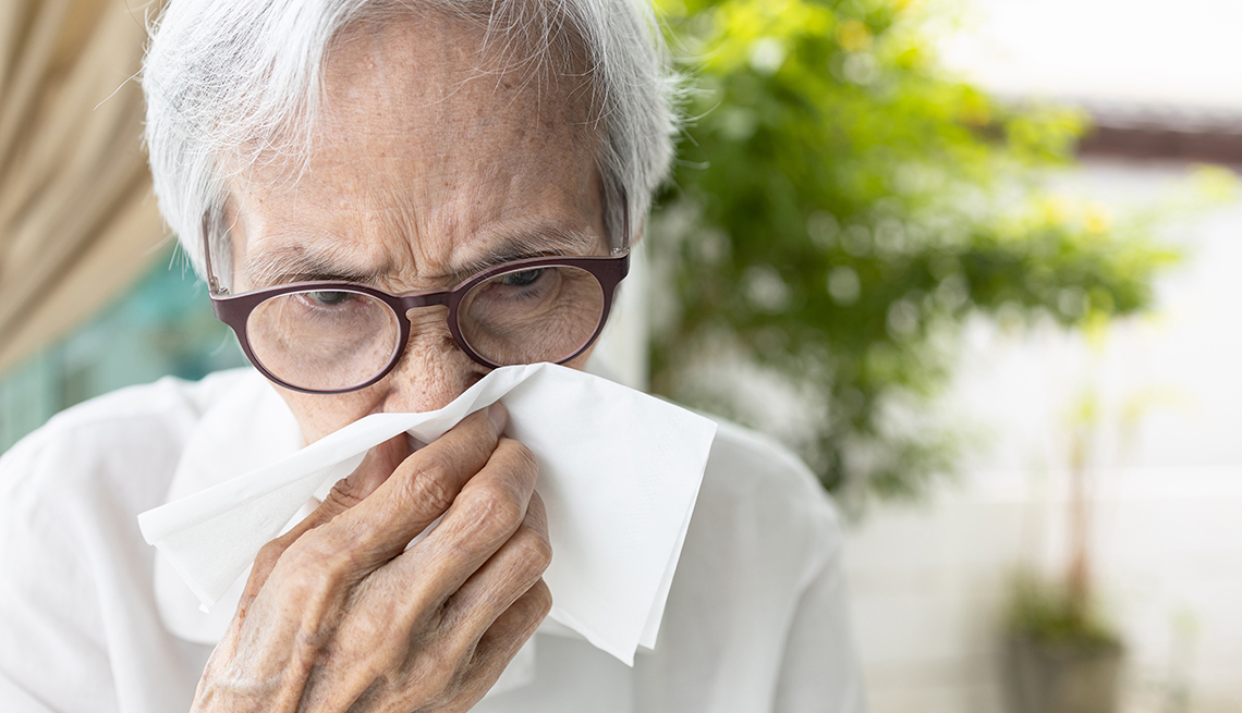 Una mujer mayor se limpia la nariz con un pañuelo desechable