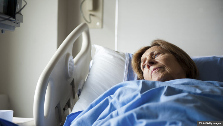 Patient in hospital bed looking pensively at the window, the cost of being labeled observed vs. admitted when at the hospital