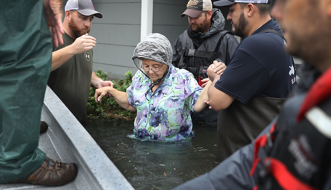 Brigada de rescate socorriendo a una anciana en medio de un desastre natural