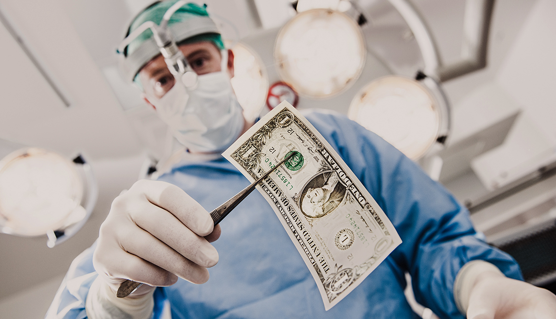 Médico sosteniendo un dólar con una pinza quirúrgica