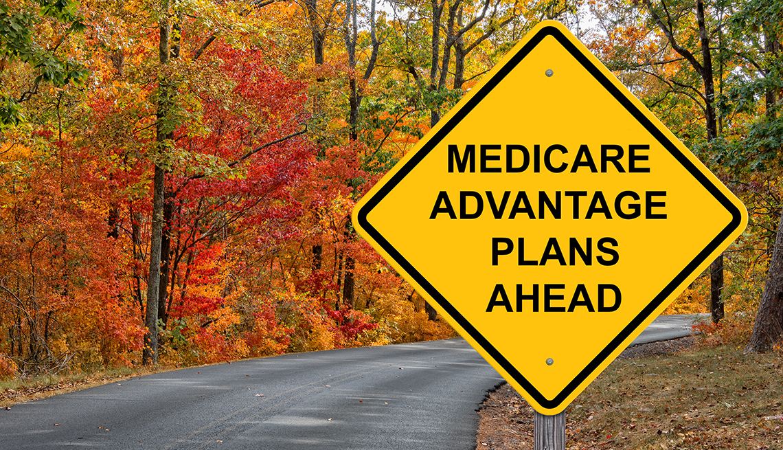 Carretera con árboles de otoño y un letrero vial que dice planes  Medicare Advantage adelante