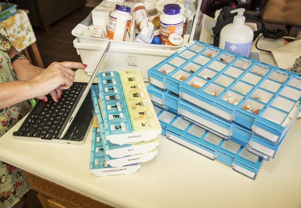 Amy refilling pills while working, Juggling Work and Caregiving (Beth Perkins Photography)