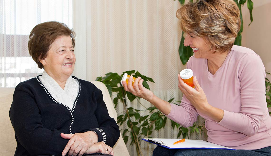 Cómo consumir los medicamentos correctamente - Mujer sostiene medicamentos en las manos mientras habla con otra mujer